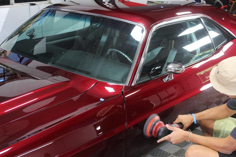 man detailing red car